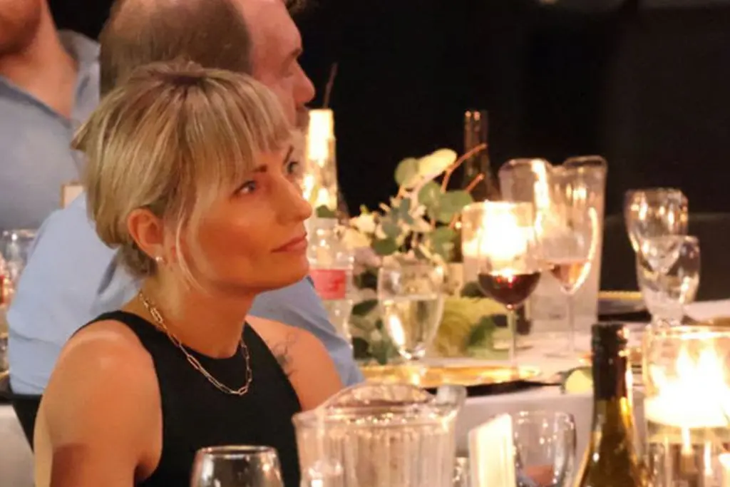 Guest seated at a candle-lit dinner table attentively listening during an evening event